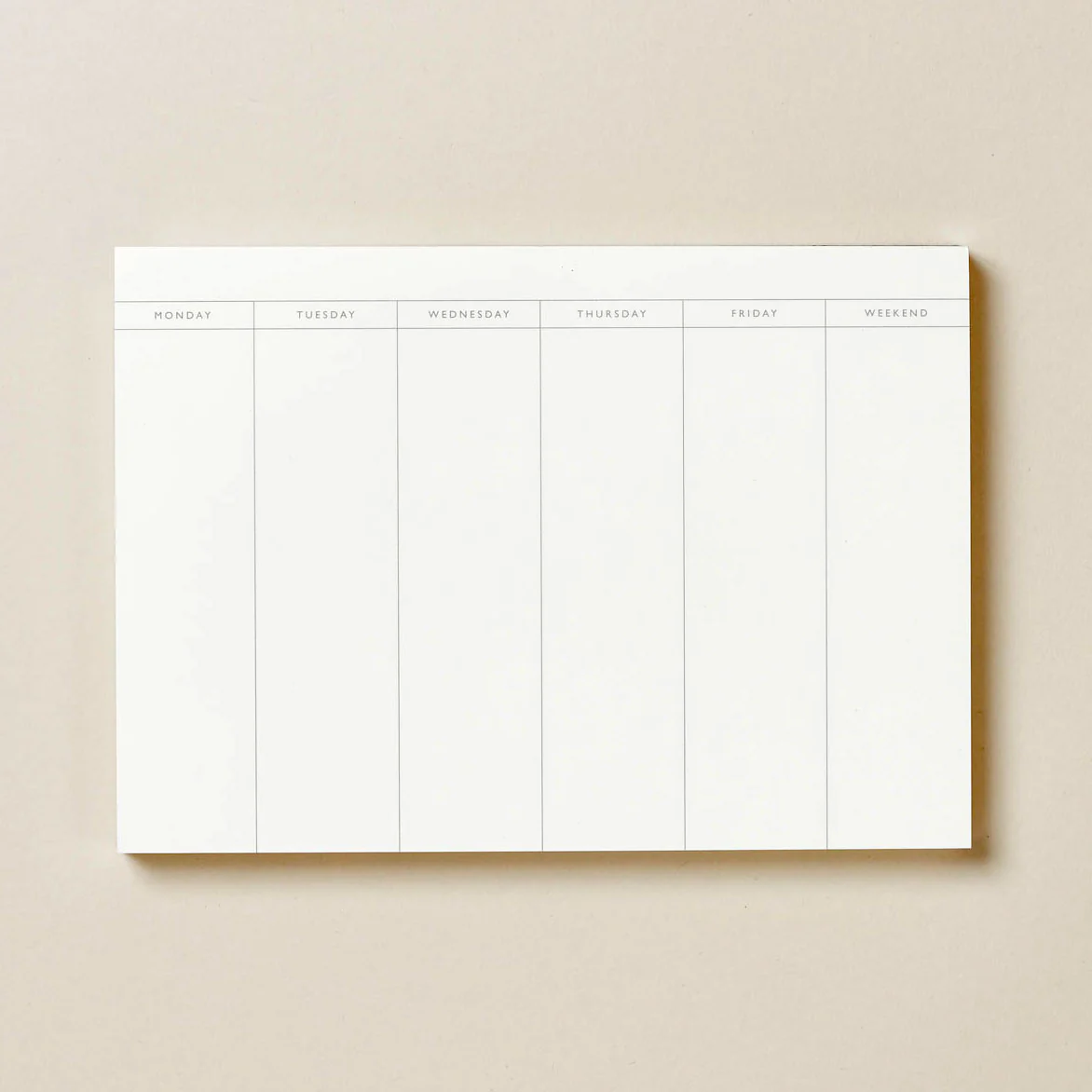 Open weekly planner spread on a linen desk surface with a pencil and minimal handwritten schedule
